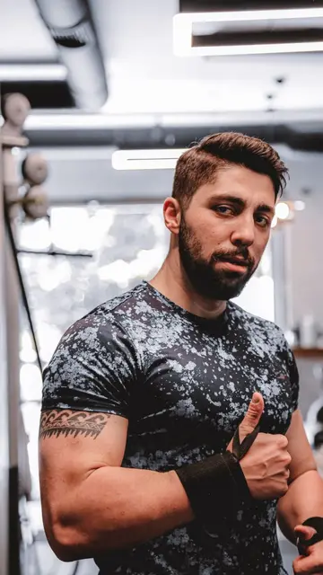 Placement still — Muscular man with short hair in gym, giving a thumbs up, wearing sportswear.