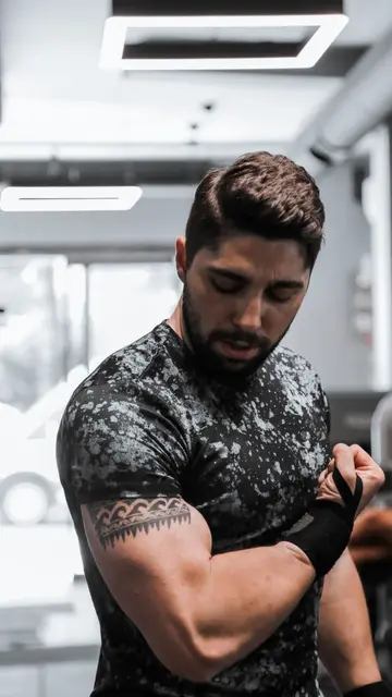 Placement still — A strong, muscular man flexes his biceps in a gym with modern equipment.